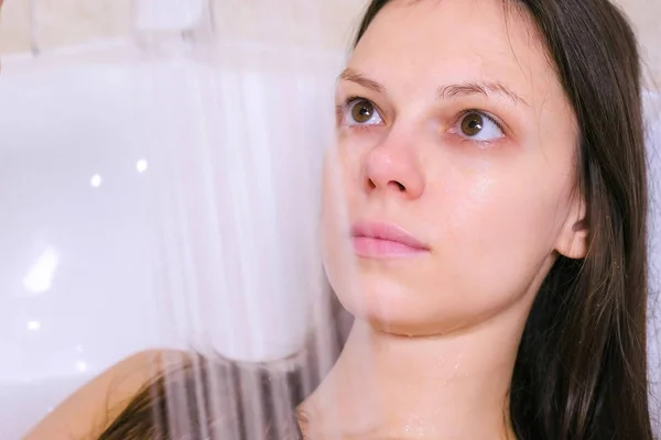 여자는 목욕을 하고있다. 그녀는 그녀의 시체는 샤워에서 물을 따른다. 얼굴 클로즈업. — 스톡 사진