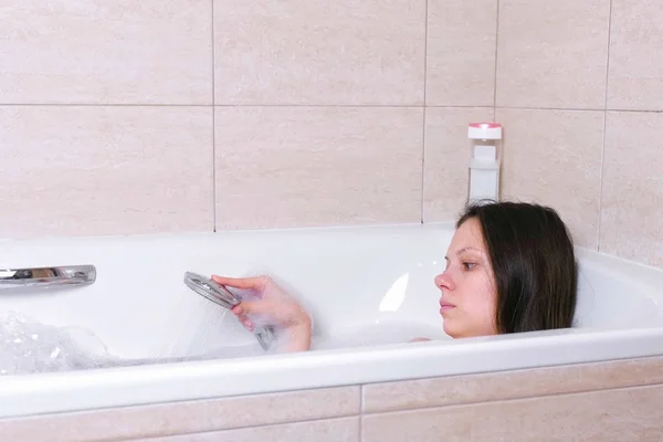 Vrouw is het nemen van een bad met schuim. Ze stroomt haar lichaam water uit de douche. — Stockfoto