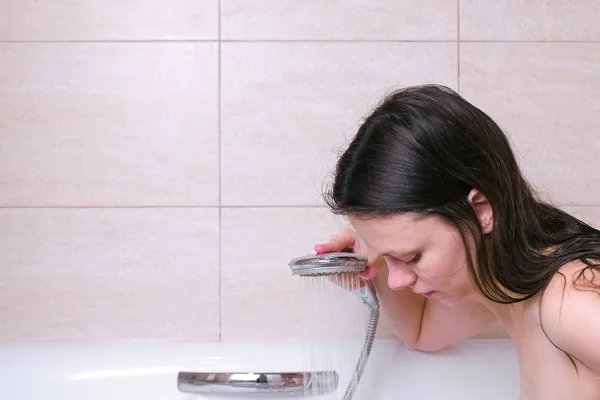 Vrouw is het nemen van een bad. Ze stroomt haar lichaam water uit de douche. — Stockfoto