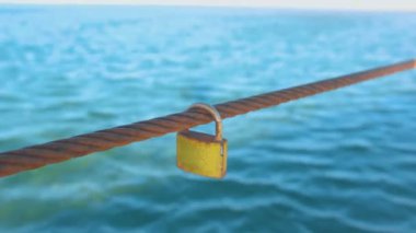 Rusty Padlock demir tel deniz su arka plan üzerinde asılı.