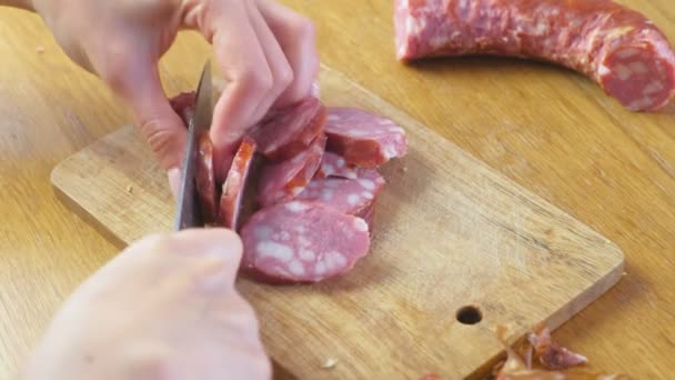 As mãos das mulheres estão cortando a salsicha defumada para fatias e pedaços . — Vídeo de Stock