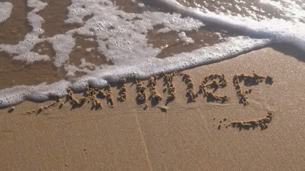 Palavra Verão escrito na areia do mar. Ondas lavaram a inscrição . — Vídeo de Stock
