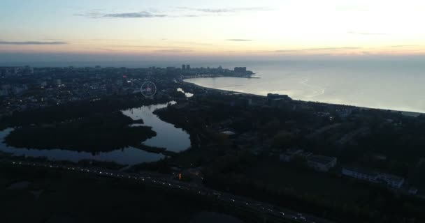 Hermosa vista nocturna de la ciudad costera con el río que fluye en el mar en la puesta del sol . — Vídeos de Stock