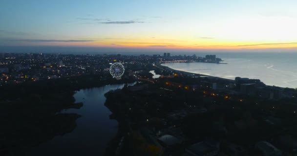 Hermosa vista nocturna de la ciudad costera con el río que fluye en el mar en la puesta del sol . — Vídeos de Stock