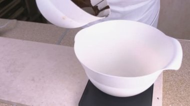 Cook üzerinde ölçekler ayakta beyaz bir kase içinde sıvı koyu çikolata dökülen. Yakın çekim görünümü.