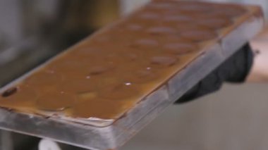 Fırıncılar eller formundan bir spatula ile aşırı çikolata kaldırır.