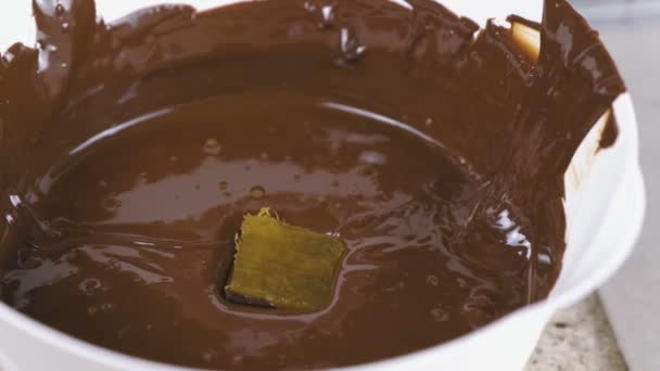 Las manos de los panaderos sumergen los dulces en chocolate derretido. Producción de caramelos de chocolate . — Vídeo de stock