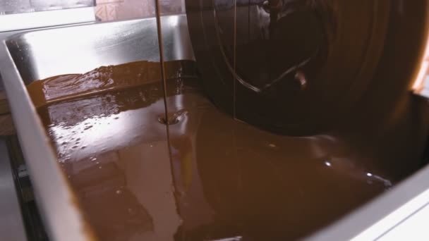 Chocolate líquido caliente en la máquina de templado de chocolate. Vista de cerca. Producción de caramelos de chocolate . — Vídeos de Stock