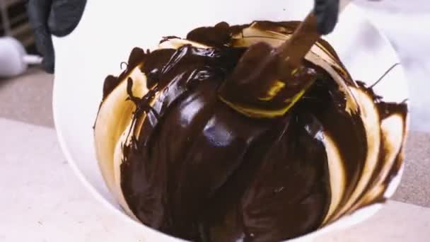 Смешайте жидкий темный шоколад в белой миске с лопаткой. Крупный план . — стоковое видео