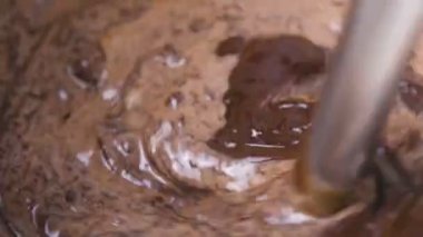 Mix blender ile sıvı koyu çikolata ve beyaz bir kase krem. Yakın çekim görünümü.