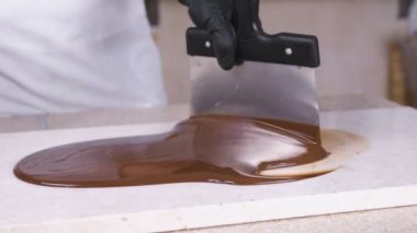 Erimiş çikolatayı doğal taşın üzerinde ısıtmak. Kadın eli ve spatula yakın plan..