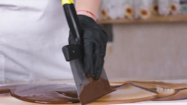 Temperar o chocolate derretido na pedra natural. Mãos femininas e espátula close-up. — Vídeo de Stock