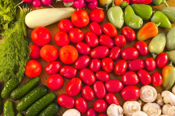 Legumes frescos tomates, pepinos, abobrinha, pimentas, verduras, rabanetes e cogumelos na mesa da cozinha . — Fotografia de Stock