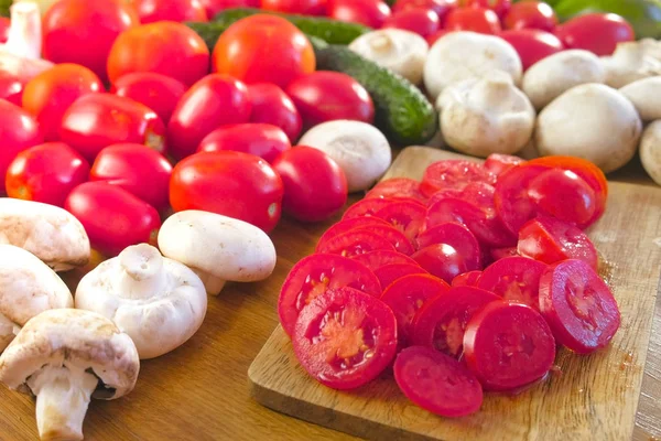 Vista de cerca de las verduras frescas y el corte de tomates en tablero de madera en la mesa de la cocina. Cámara rotar . — Foto de Stock