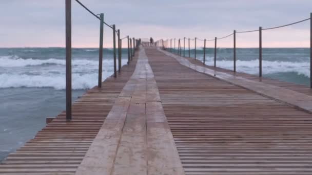 Wellen plätschern durch den hölzernen Pier im Meer. Familie am Pier bei Sonnenuntergang. wunderschöne Meereslandschaft. — Stockvideo