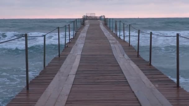 Волны брызгают через деревянный пирс в море. Красивый морской пейзаж на закате . — стоковое видео