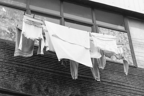Концепция жизни в бедности. Постельное белье высушивается на балконе на улице. Вид сбоку. Черное и белое . — стоковое фото