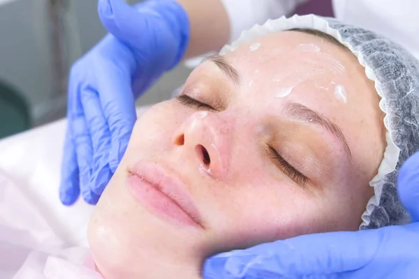 Estetista mette la crema sul viso delle donne. Trattamento viso cosmetologo. Primo piano . — Foto Stock