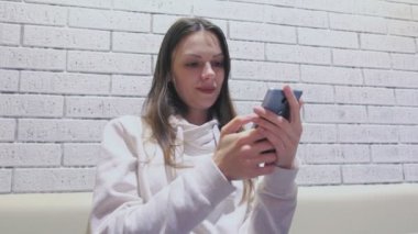 Kadın oturuyor ve biri kafede bekliyorum cep telefonunda bir mesaj yazarak.