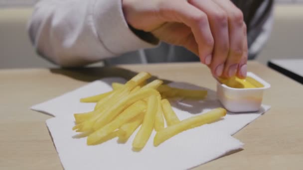 Mulher comendo batatas fritas com molho de queijo no café. Mãos fechadas . — Vídeo de Stock