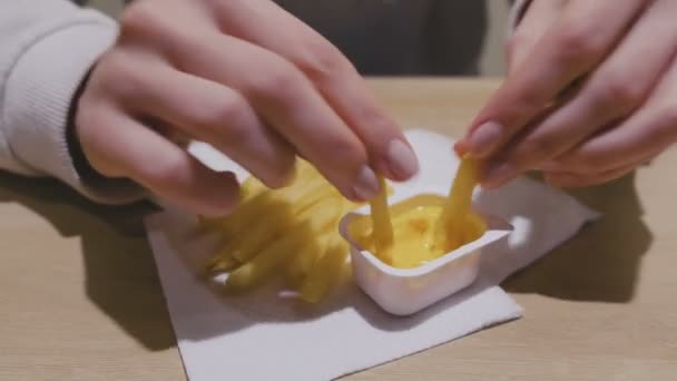 La donna sta mangiando patatine fritte con salsa al formaggio al caffe '. Mani in primo piano . — Video Stock