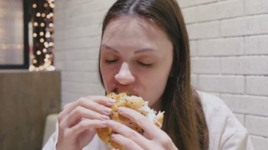 Kafede hamburger zevkle ve zevk ile yemek kadın.