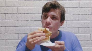 Adam kafede zevkle ve zevk ile bir hamburger yiyor.