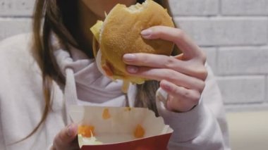 Kadın kafede hamburger yiyor. Yakın çekim yakışıklı.