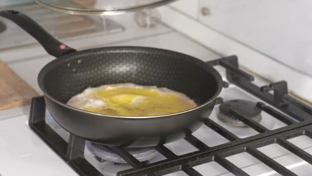 Mans main ferme le couvercle de la préparation des œufs brouillés avec de la saucisse dans une poêle sur une cuisinière à gaz . — Video
