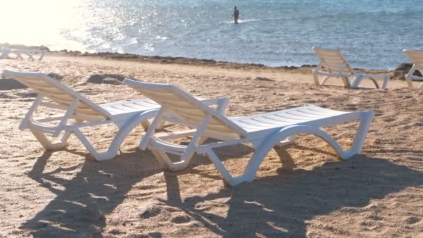 Zwei Sonnenliegen am Sandstrand in der Nähe des Meeres. — Stockvideo