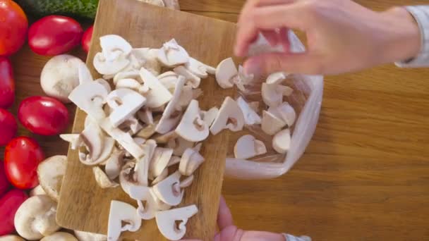 Les mains des femmes mettent les champignons dans un sac sur la table de cuisine . — Video