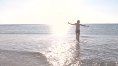 Çocuk deniz suyu tarafından günbatımı üzerinde yürüyor. Denizde yüzme.