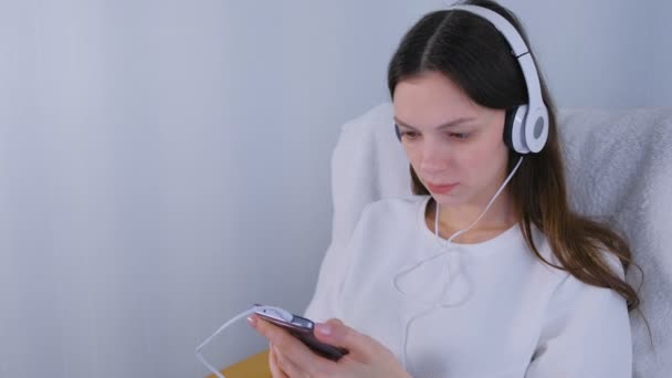 Kobieta jest słuchanie muzyki w słuchawkach na smartphone. — Wideo stockowe