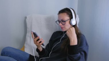 Genç kadın gözlük ve kulaklık Smartphone cep telefonu ile bir müzik dinleme ve içinde karaoke şarkı.