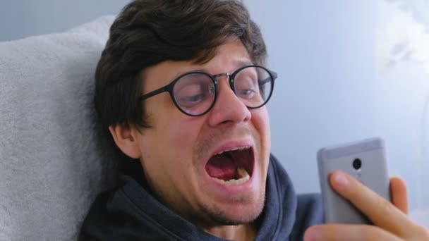 Człowiek w okularach bada jego zębów za pomocą aparatu w telefonie komórkowym. — Wideo stockowe
