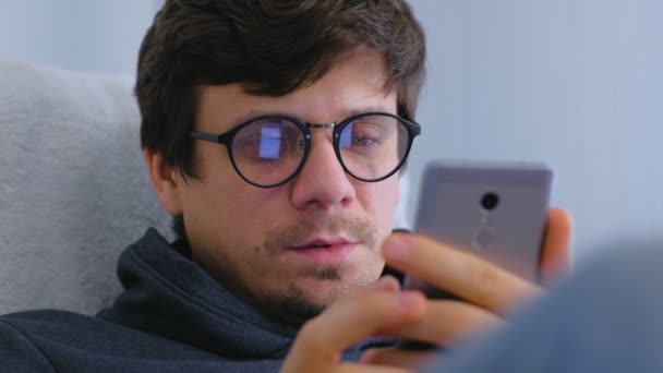 Mann mit Brille kauft im Online-Shop und surft auf dem Smartphone. Gesicht aus nächster Nähe. Online-Einkauf. — Stockvideo