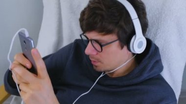 Adam akıllı telefon kulaklıktan müzik dinler ve bir şarkı söyler. Saat akşam sakin ol.