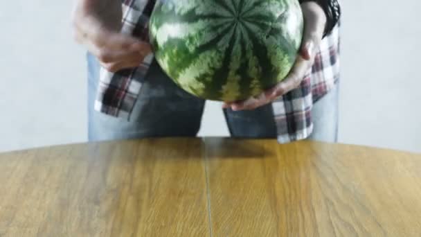 Az ember egy görögdinnye csavarják a konyhaasztalon. Közeli kezek. — Stock videók
