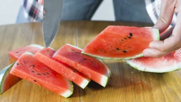 Člověk řeže meloun na malé plátky na kuchyňském stole. Rukou zblízka. — Stock video