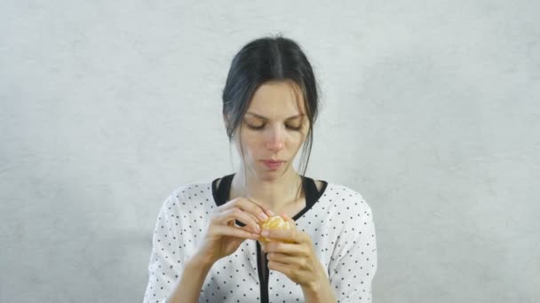 Las emociones de lo dulce en la cara de las chicas. Mujer morena comiendo mandarina dulce y sonriendo . — Vídeos de Stock