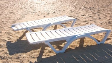 Yaz kum plajında iki sunlongers.