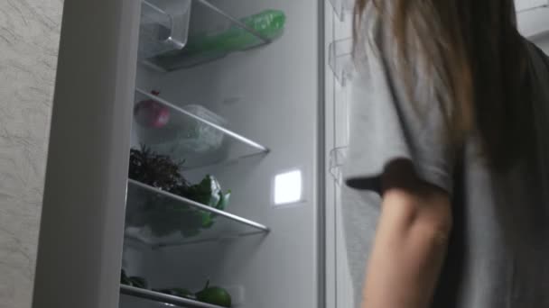 A mulher tira as tangerinas do frigorífico à noite. Visão traseira . — Vídeo de Stock