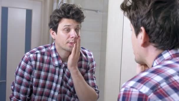Moe slaperig gewekt man met een kater in de badkamer, kijkt naar de spiegel en plaatst zichzelf in volgorde. — Stockvideo