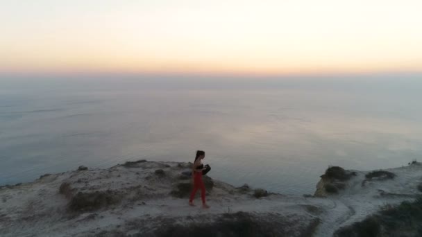 Kvinnan promenader på kanten av en klippa med en yoga matta. — Stockvideo