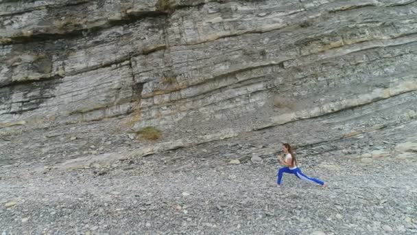 Frau macht Yoga und Stretching-Übungen auf Felsen und Meer Hintergrund. Luftbild schöne Aufnahmen Seitenansicht. — Stockvideo