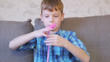 Mutlu çocuk parmak pembe bir sümük koç üzerinde oturan ve oyun makaraları.