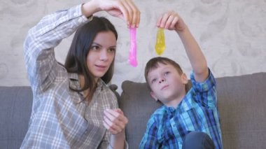 Mutlu anne ve oğlu kanepede oturan balçık ile oynuyorlar. Sümük germe.