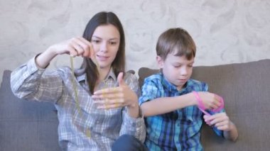 Mutlu anne ve oğlu kanepede oturan balçık ile oynuyorlar. Sümük germe.