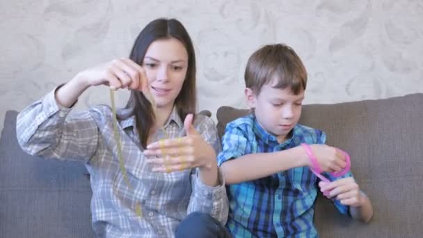 Mãe e filho felizes estão brincando com lodo sentado no sofá. Lamas de alongamento . — Vídeo de Stock