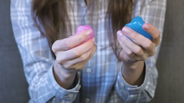 As mãos das mulheres amassam, apertam e esticam um lodo rosa e azul. Mulher brinca com lodo . — Vídeo de Stock